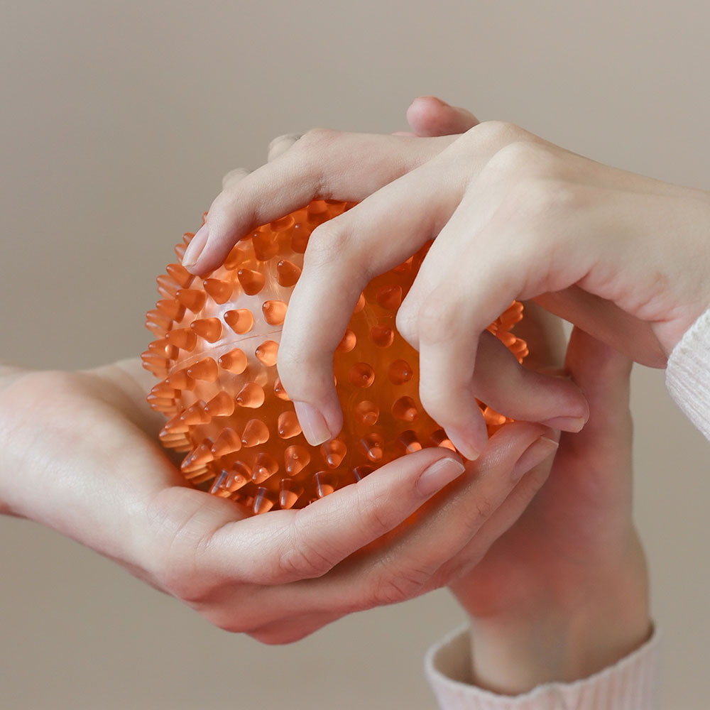 Hands holding an orange exercise ball